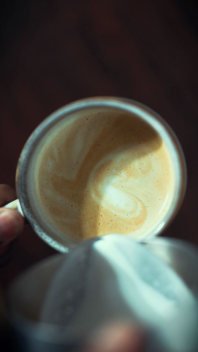 A flat white with latte art, poured in the morning light